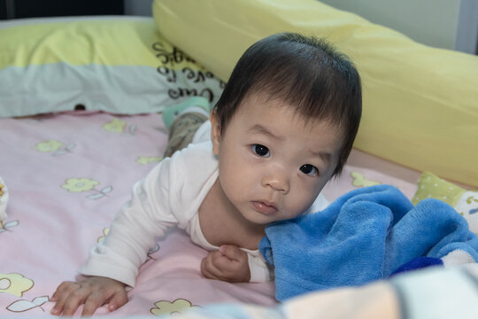 Portrait Adorable and happy Chinese baby boy on tummy time on bed. Newborn child relaxing in bed