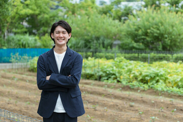 畑で腕組みをする若い男性・新しい農業