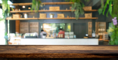 Empty wooden table top with abstract blurry image of coffee shop or cafe restaurant in background for product showing and advertising.
