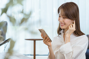 ワイヤレスイヤフォンで音楽を聞く女性・動画配信