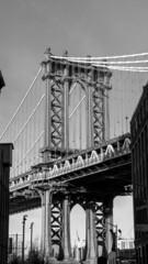 Naklejka premium Manhattan Bridge between Manhattan and Brooklyn over East River seen from a narrow alley enclosed by two brick buildings on a sunny day in Washington street in Dumbo, Brooklyn, NYC