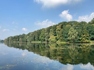 Fototapeta na wymiar Landschaft am See mit Spiegelung der Bäume im Wasser
