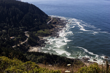 View from a hill overlooking the Oregon coast while waves crash into surrounding areas.