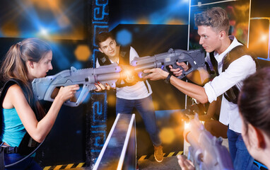 Two emotional cheerful smiling players standing opposite each other with laser pistols in laser tag...