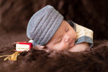A cute Asian infant Muslim in thobe with prayer cap on bed in home, translation is noble quran