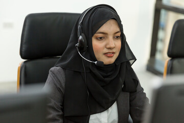 Asian Muslim woman in hijab headscarf customer support operator with headset at work. Muslim female...