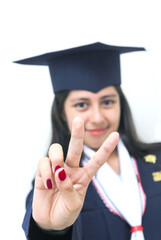 Chica feliz con toga y gorro de graduacion, seña de amor y paz con la mano