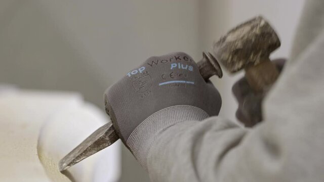 Craftsman working on historic stone element with hammer and chisel