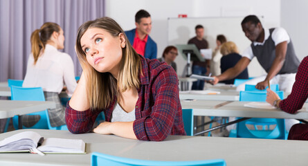 Obraz premium Portrait of unhappy girl sitting apart in class, having conflict with fellows students