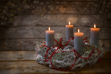 Advent wreath of branches with burning candles and red chain decoration, tradition in the time...