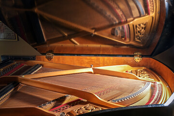 Inside a grand piano with mirroring of frames and strings in the open lid of the musical...