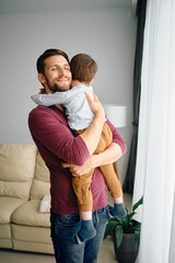 Affectionate father embraces his small son at home.
