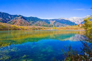 Fototapeta na wymiar Azusa River flowing through Kamikochi national park in Nagano Prefecture, Japan. The autumn leaves season is beautiful.