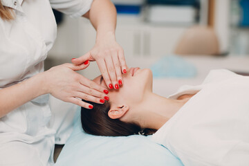 Beautiful young woman getting face treatment massage at beauty spa