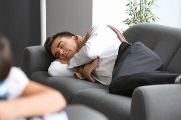 Fototapeta premium Young businessman sleeping on sofa in office