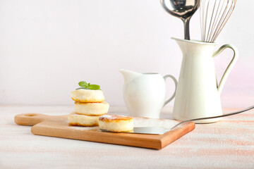 Board with tasty cottage cheese pancakes on table