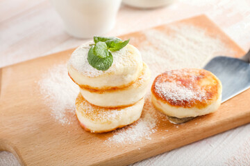 Board with tasty cottage cheese pancakes on table