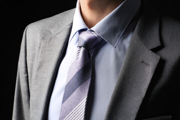 Young man in stylish suit on dark background, closeup