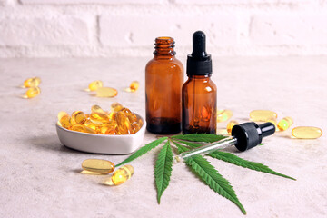 Cannabis oil in a glass bottles, pills and capsules with green marijuana leaf.