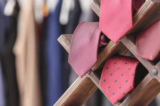 Wooden stand with different stylish neckties, closeup