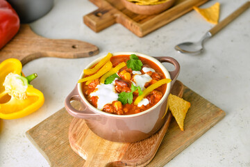 Pot with delicious chili con carne and nachos on table