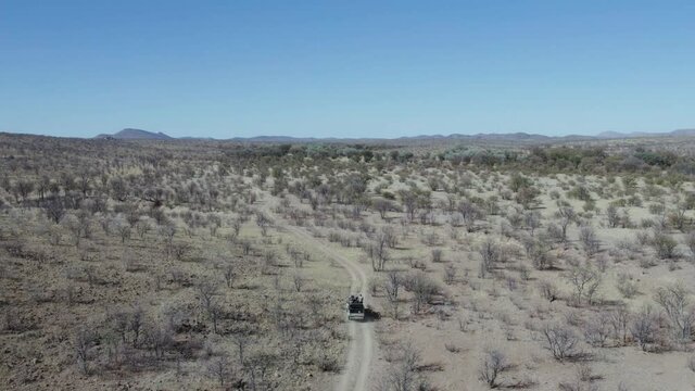 Off road vehicle driving through Namibia territory during safari, Africa. Aerial tracking descendent