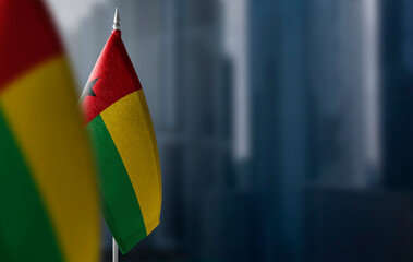 Small flags of Guinea Bissau on a blurry background of the city