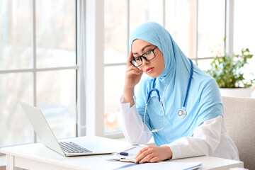 Tired Muslim female doctor working in clinic