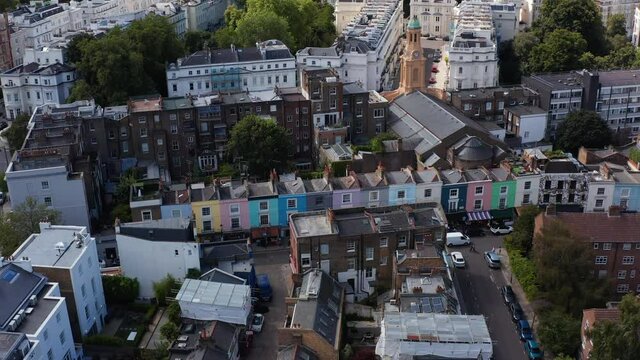 Slide and pan footage of row of houses with colourful facades. Aerial view of streets of urban neighbourhood Notting Hill. London, UK