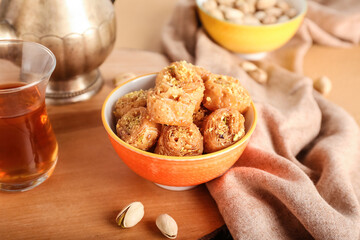 Bowl with delicious baklava and pistachio nuts on table