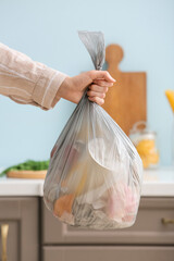 Woman holding bag with garbage at home