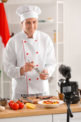 Handsome chef with garlic press recording video in kitchen
