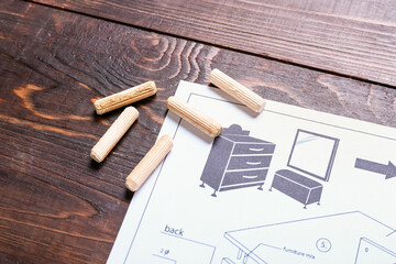 Furniture assembling plan and dowels on wooden background, closeup