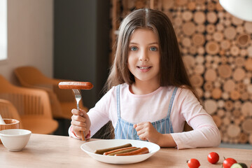 Cute little girl with tasty sausage in kitchen