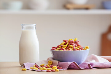 Bowl with different corn rings, napkin and bottle with milk on table