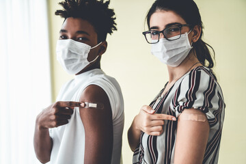 Diverse group of people showing COVID-19 vaccine bandage merrily in concept of coronavirus vaccination program to vaccinate citizen .