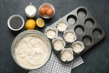 Dough for muffins with poppy seeds and baking tin on table