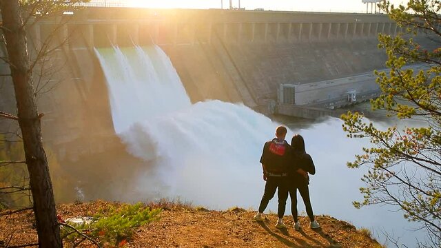 Water discharge at the Bratsk hydroelectric power station. A loving couple is watching the landscape.