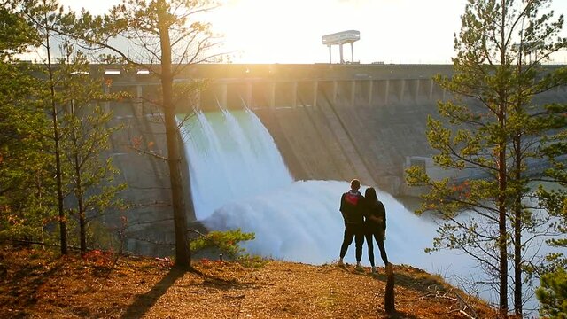 Water discharge at the Bratsk hydroelectric power station. A loving couple is watching the landscape.