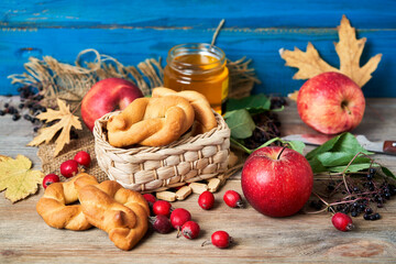 Apples, sweet brushwood and honey on a wooden table among the maple leaves