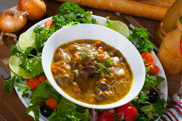 Tasty goulash with chicken hearts and vegetables served with greens and fresh baguette..