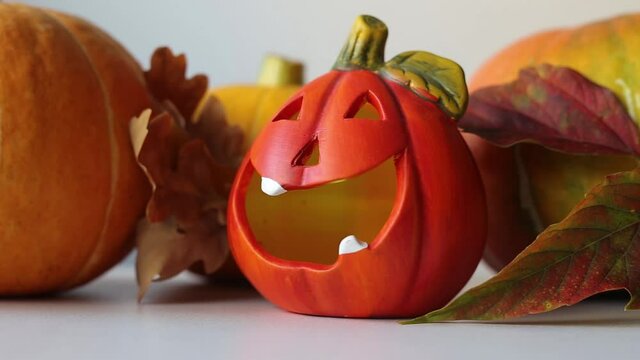 A lamp in the form of a pumpkin for Halloween, against the background of autumn leaves and pumpkins.