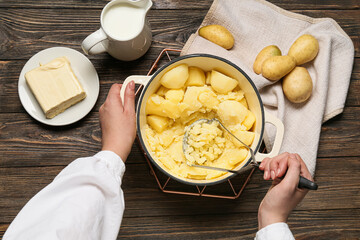 Woman preparing tasty mashed potatoes on wooden background, closeup