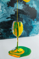 Green lime color yellow ink paints are flowing down into the glass cocktail concept 