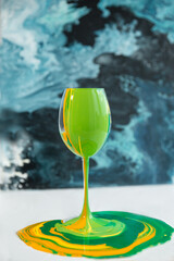 Green lime color yellow ink paints are flowing down into the glass cocktail concept  - 458873833