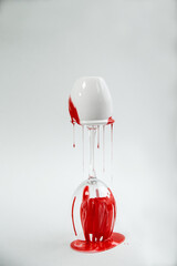 White and red acrylic liquid paints with drops are flowing down on the round shape  - 458873835