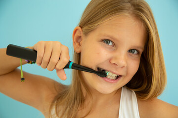 girl on a blue background with a toothbrush and teeth smiling, dentistry and brushing teeth - obrazy, fototapety, plakaty