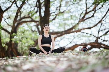 Asian woman meditating in gym clothes at the park