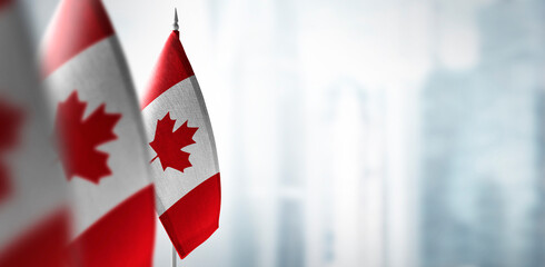Small flags of Canada on a blurry background of the city - 458874463