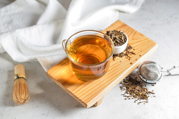 Composition with cup of tasty hojicha green tea on light background
